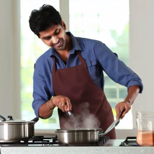 A smiling guy busy cooking.